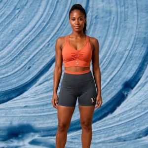 Modelo usando o Conjunto Fitness VanUnique com top terracota de alça dupla com franzido frontal e short cinza escuro de cintura alta.vest m